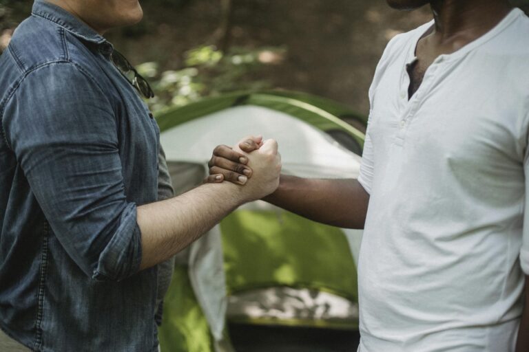 Male travelers shaking hands in campsite